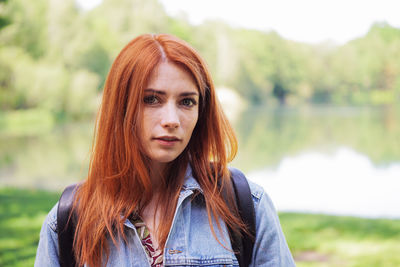 Portrait of young woman standing against trees