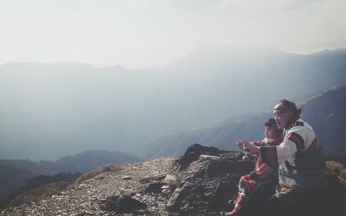 Man standing on mountain against cloudy sky