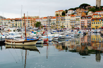 Boats moored at harbor against buildings in city