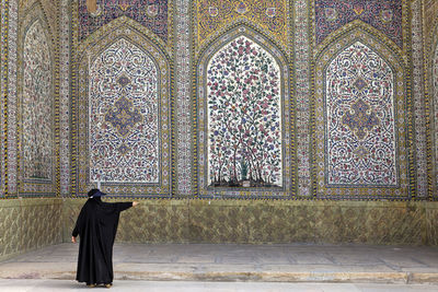 Rear view of woman standing against wall in mosque