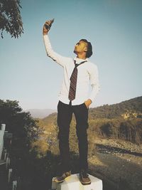 Man standing by tree against sky