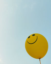 Low angle view of smiling balloons against sky