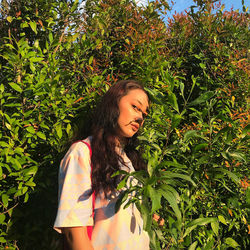 Beautiful young woman standing against plants