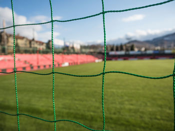 Seamless mesh fence in football stadium on blue sky.