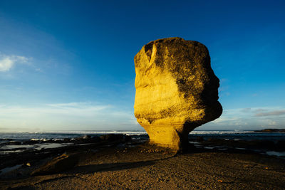 Scenic view of rock on beach against sky during sunset