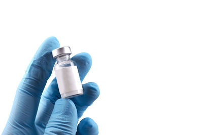 Close-up of hand holding bottle against white background