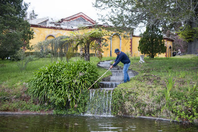 Man holding umbrella by river against building