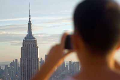 Rear view of man photographing new york cityscape and empire state