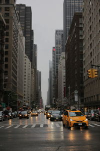 Traffic on city street by buildings against sky