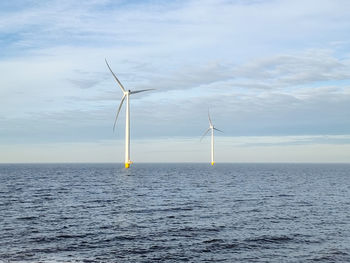 Wind turbines in sea against sky