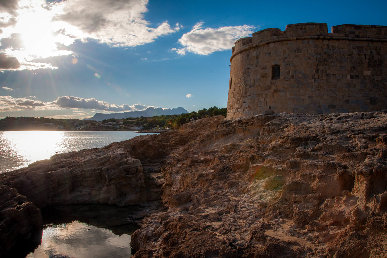 sky, architecture, history, built structure, the past, water, nature, wall, cloud - sky, building exterior, sunlight, solid, day, fort, rock, travel, no people, ancient, outdoors, stone wall, ruined