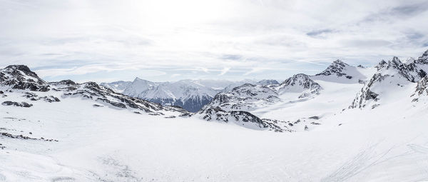 Scenic view of snowcapped mountains against cloudy sky