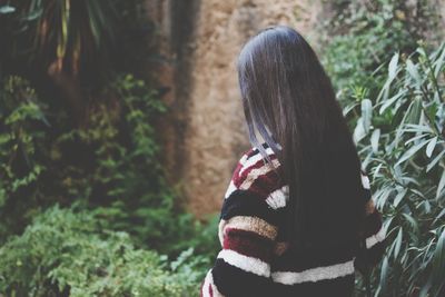 Side view of woman with long hair standing by plants in park