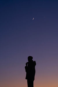 Silhouette man standing against moon at sunset