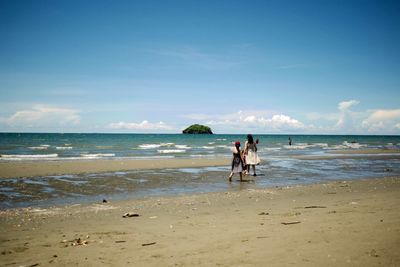 People at beach against sky