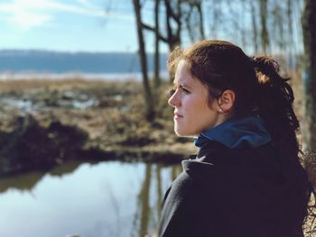 Side view woman looking away while standing by lake