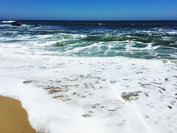 Surf on beach against blue sky