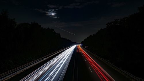 Light trails on road against sky at night