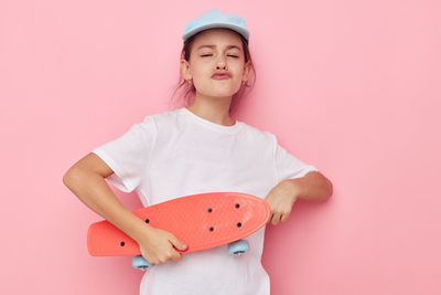 Portrait of cute girl with gift against pink background