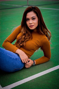 Portrait of young woman sitting on sports track