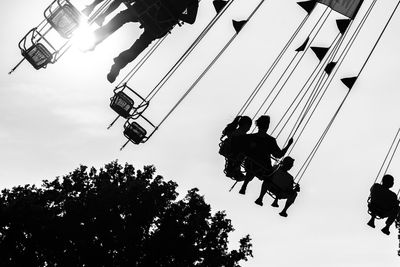 Low angle view of silhouette chain swing ride against sky