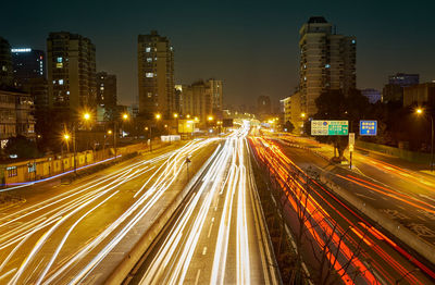 High angle view of light trails on road amidst buildings at night