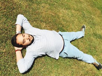 Full length of man resting on grassy land in park during sunny day