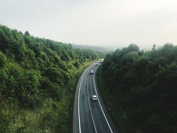 High angle view of cars moving on road amidst trees against sky