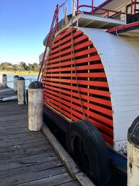 Red boat moored on shore against sky