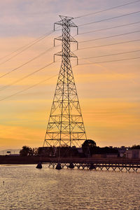 Silhouette electricity pylon against sky during sunset