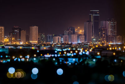 Defocused image of illuminated lights against buildings at night