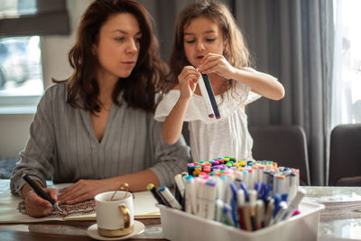 Mother and daughter drawing while sitting at home