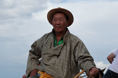 Low angle portrait of man wearing hat against sky