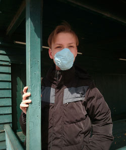 Portrait of young man standing against metal