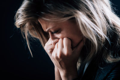 Close-up of depressed woman against black background