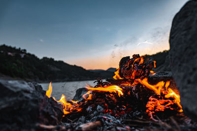 Bonfire on rock against sky during sunset