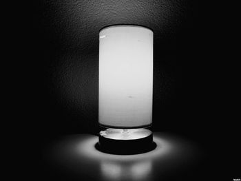 Close-up of illuminated light bulb on table against wall