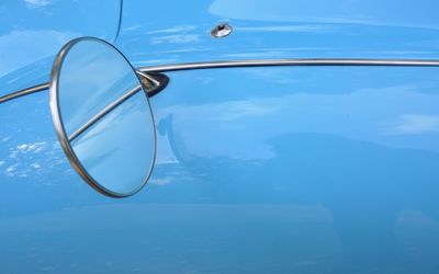 Close-up of cropped car against blue sky