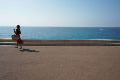 Woman on sea shore against sky