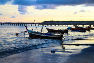 Boats moored in sea at sunset
