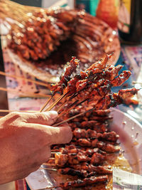 Midsection of person holding satay at market