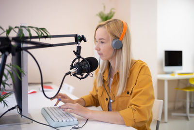 Woman wearing headphones working on computer at internet cafe