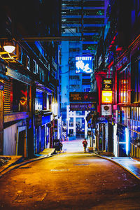 Illuminated street amidst buildings in city at night