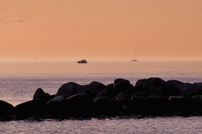 Sailboat sailing in sea at sunset