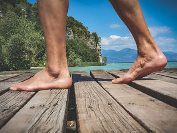 Low section of man legs on wood against sky