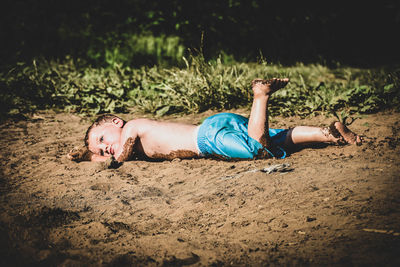 Side view of baby lying on sand