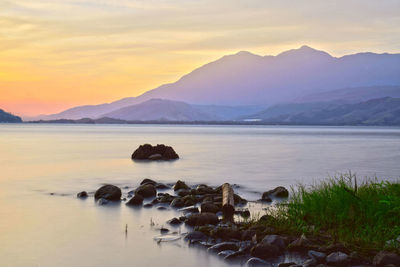 Scenic view of lake against mountains during sunset