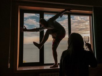 Rear view of woman standing against window