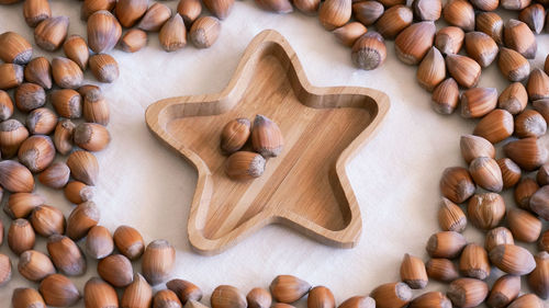 Bamboo star shape plate with three hazelnuts in it on natural fabric background 