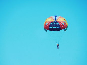 Low angle view of parachuting against clear blue sky